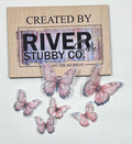 Purple edible wafer paper butterfly cake charms arranged below a Riverside Stubby Co wooden sign