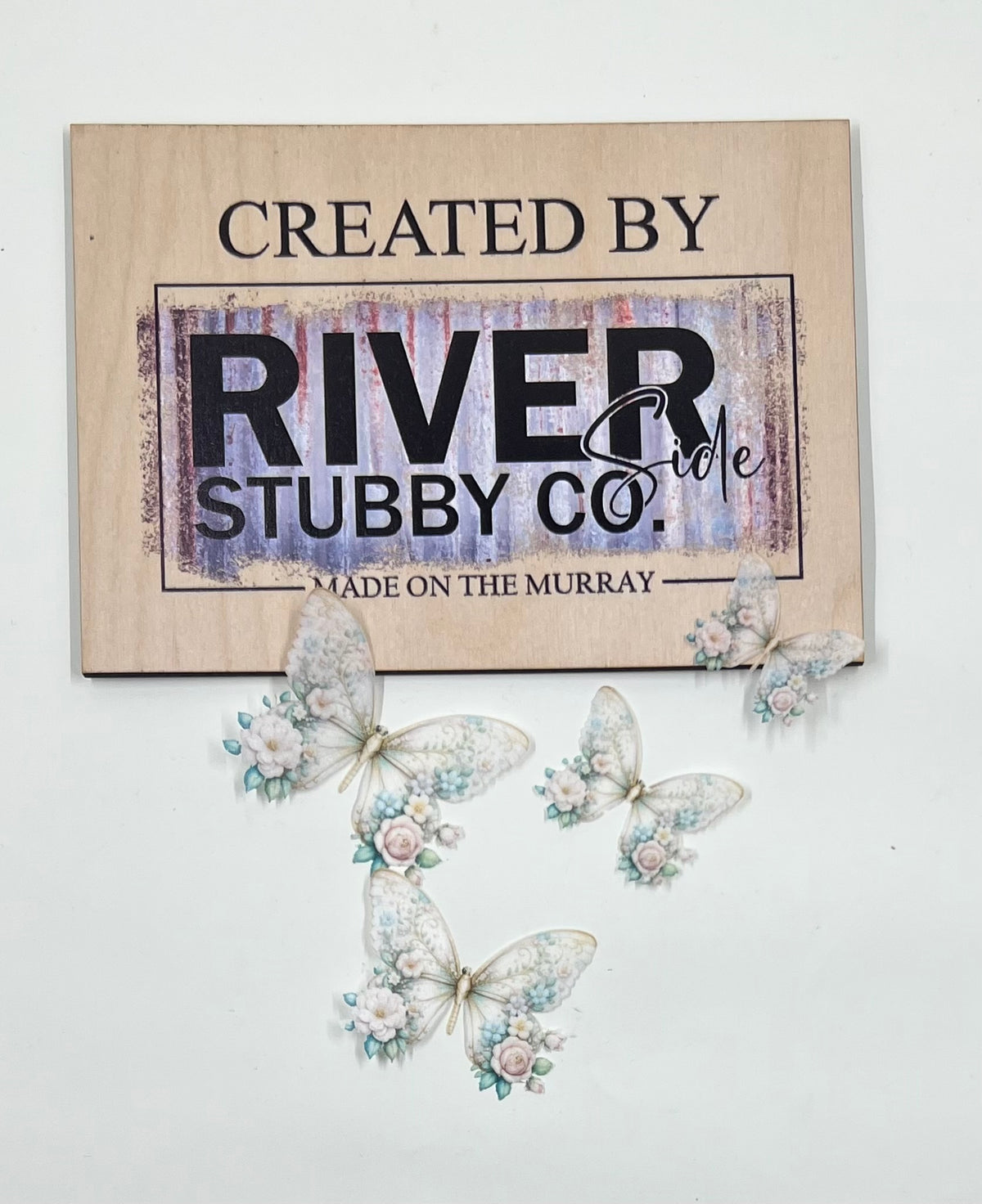 White floral edible wafer paper butterfly cake charms arranged below a Riverside Stubby Co wooden sign