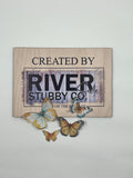 Orange edible wafer paper butterfly cake charms arranged below a Riverside Stubby Co wooden sign