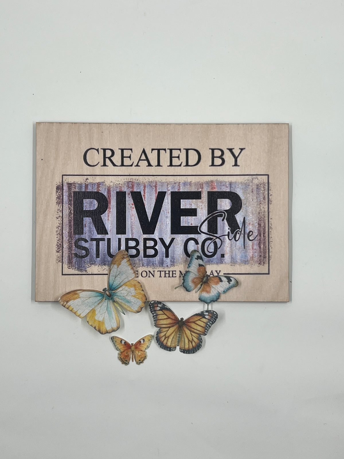 Orange edible wafer paper butterfly cake charms arranged below a Riverside Stubby Co wooden sign